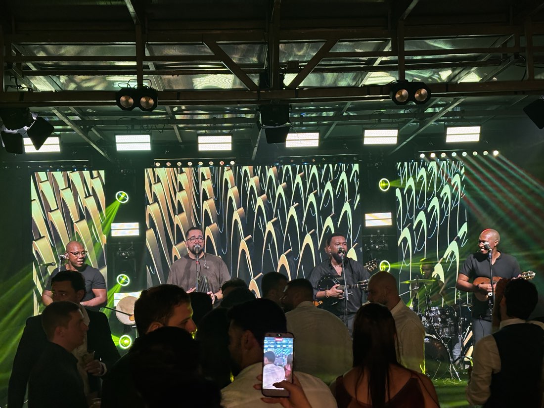 Pista cheia diante do palco, com o grupo tocando sob a luz verde