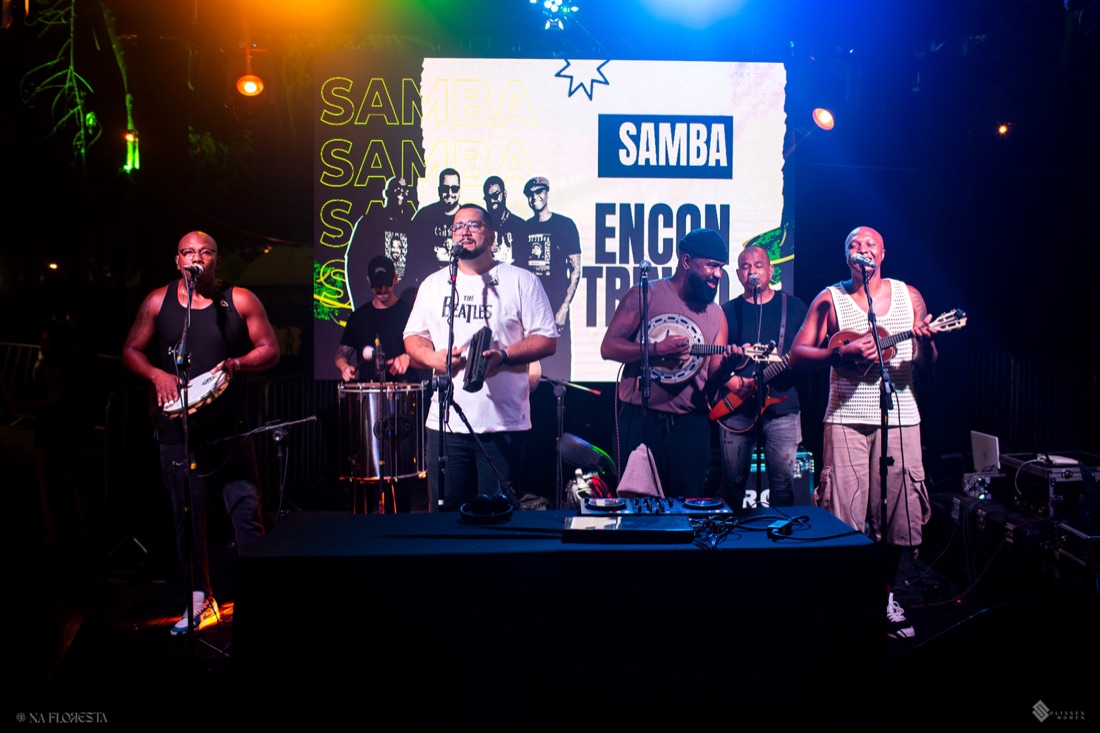 Projeto Encontrinho tocando ao vivo, com o painel do grupo ao fundo